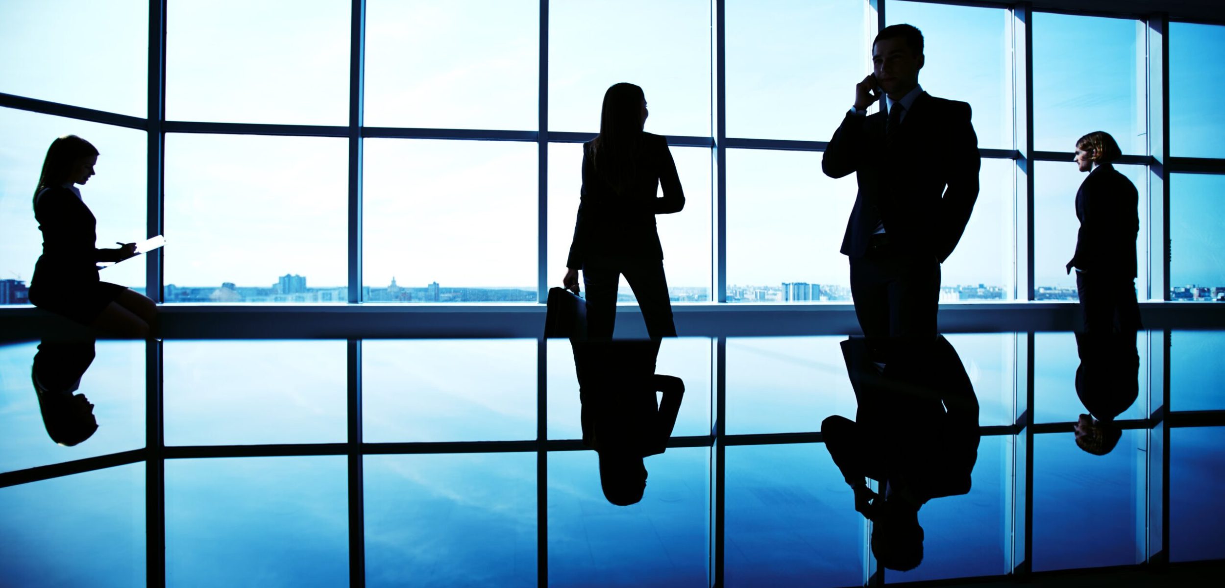 Silhouettes of several office workers working on background of window